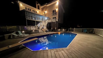 A swimming pool on a wooden deck with a multi-level building in the background.