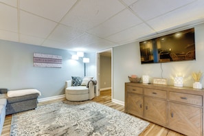A living room with a grey sofa, a patterned rug, a television mounted on the wall, and a cabinet with decorative items.