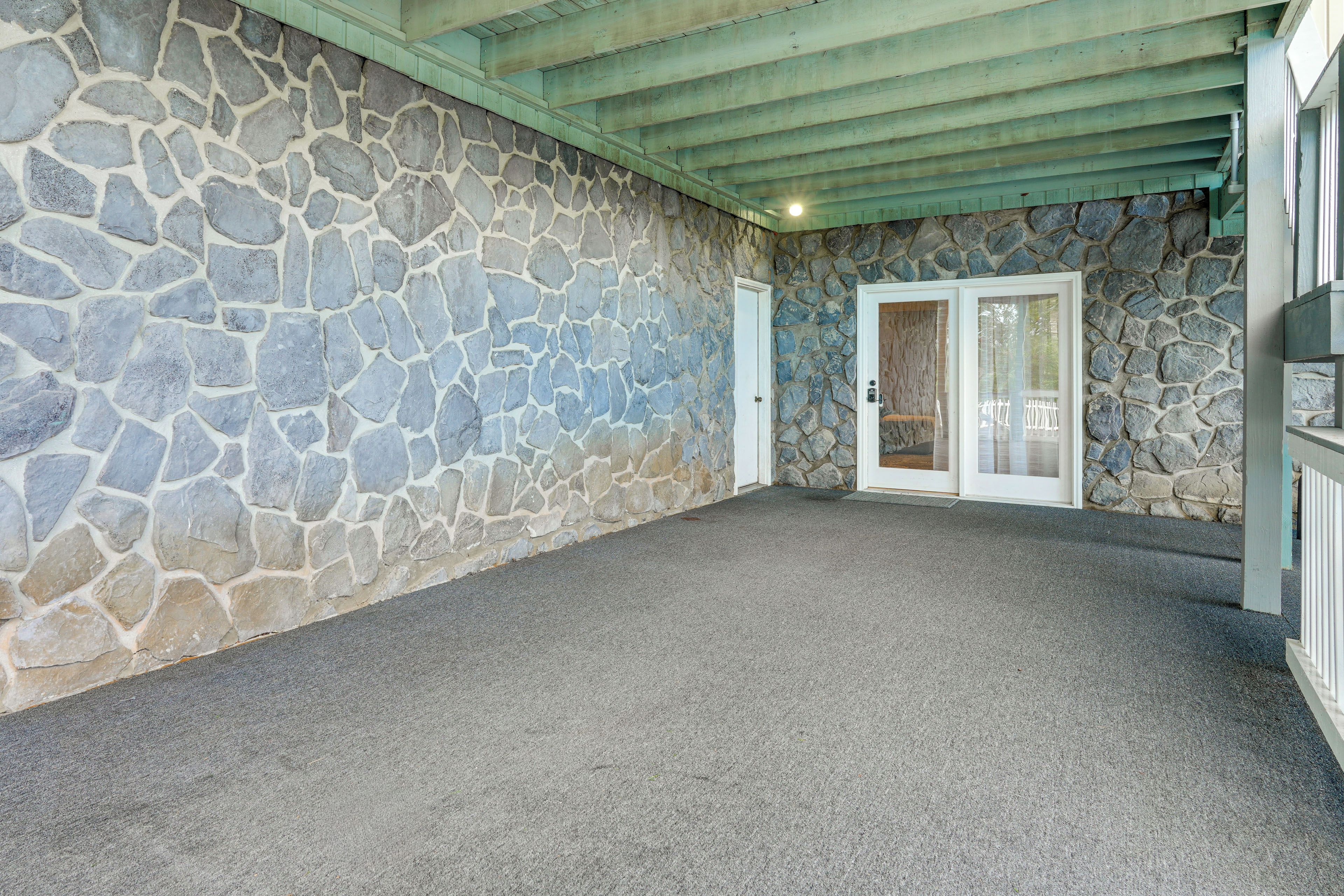 A stone-walled room with a grey carpet, a wooden ceiling, and a door with a glass panel.