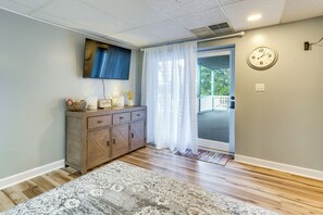 A room with a wooden cabinet, a television mounted on the wall, a patterned rug, and a door with a glass panel. - Tri-cities Home Near Lakes & Bristol Speedway (Blountville)