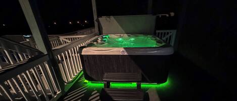 Un jacuzzi con iluminación verde en un balcón.