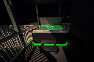 A hot tub with green lighting on a balcony.