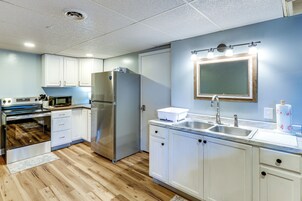 A modern kitchen with white cabinets, stainless steel appliances, a double sink, and a wooden floor.