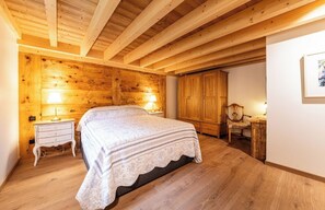 Ein Schlafzimmer mit Holzwänden, einem Bett, Nachttischen und einem Sessel.
