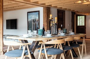 Ein Essbereich mit einem langen Holztisch, gedeckt für sechs Personen, umgeben von Stühlen mit gepolsterten Sitzen.