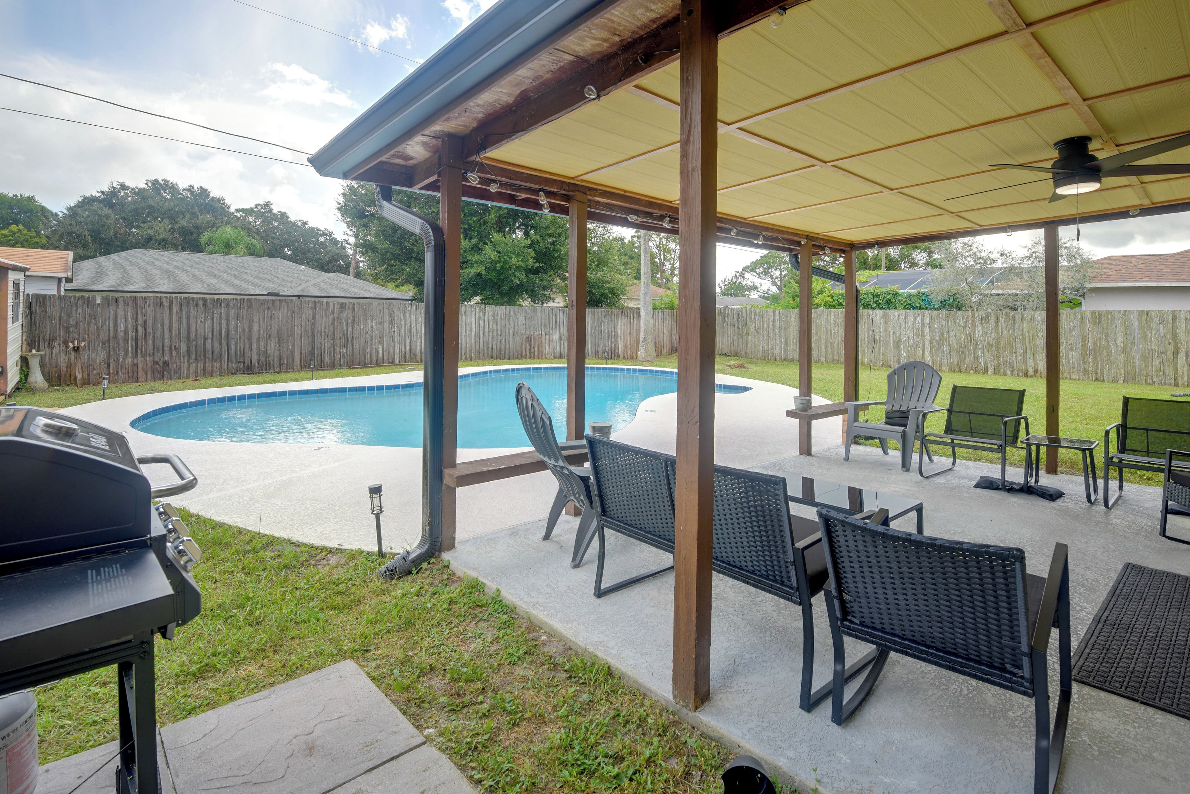 A backyard with a swimming pool, outdoor furniture, and a barbecue grill.