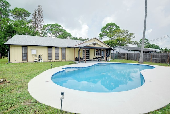 A residential property with a swimming pool, a covered patio, and a detached garage.