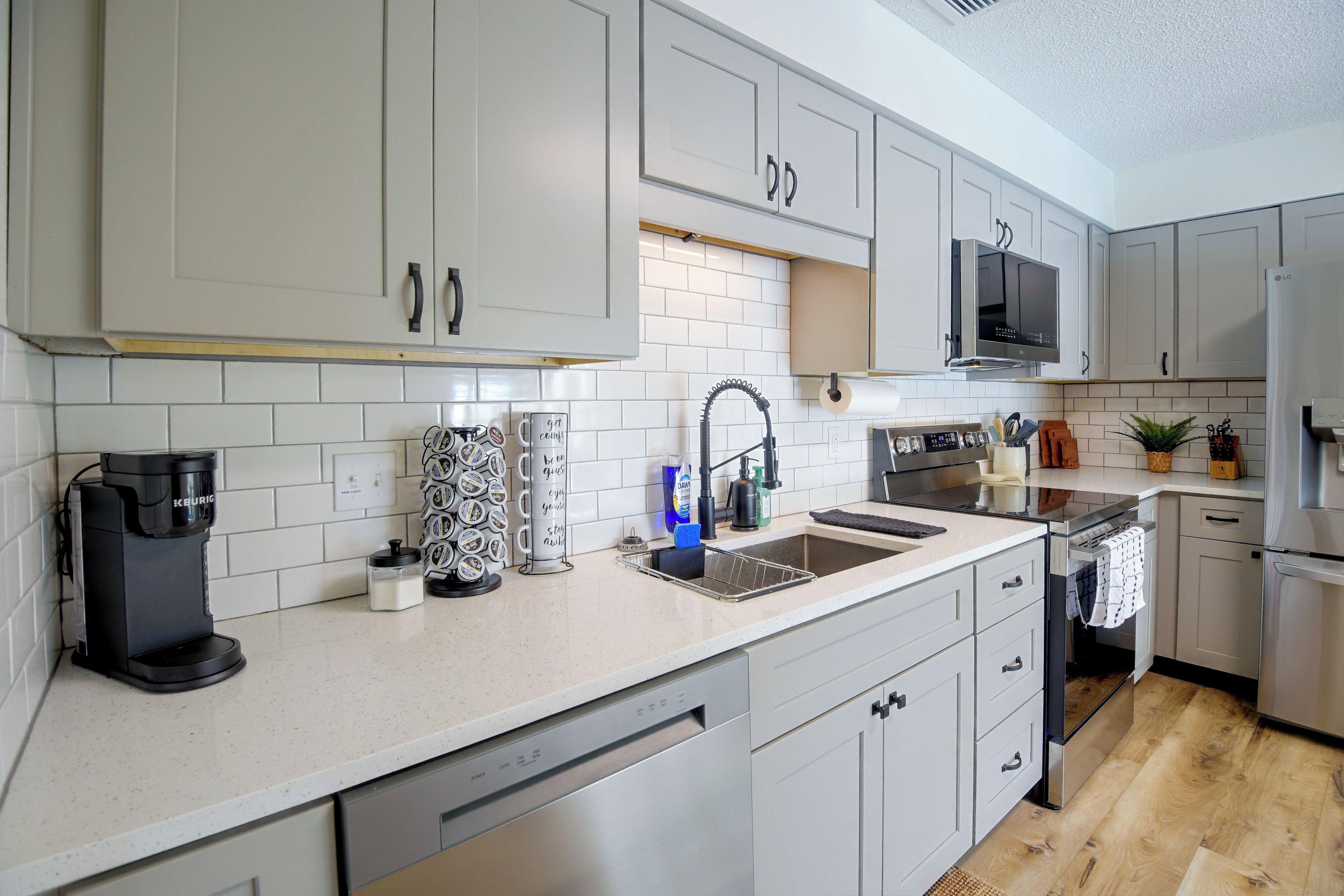 A modern kitchen with white cabinetry, a built-in dishwasher, and a coffee maker.