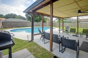 A backyard with a swimming pool, outdoor furniture, and a barbecue grill.