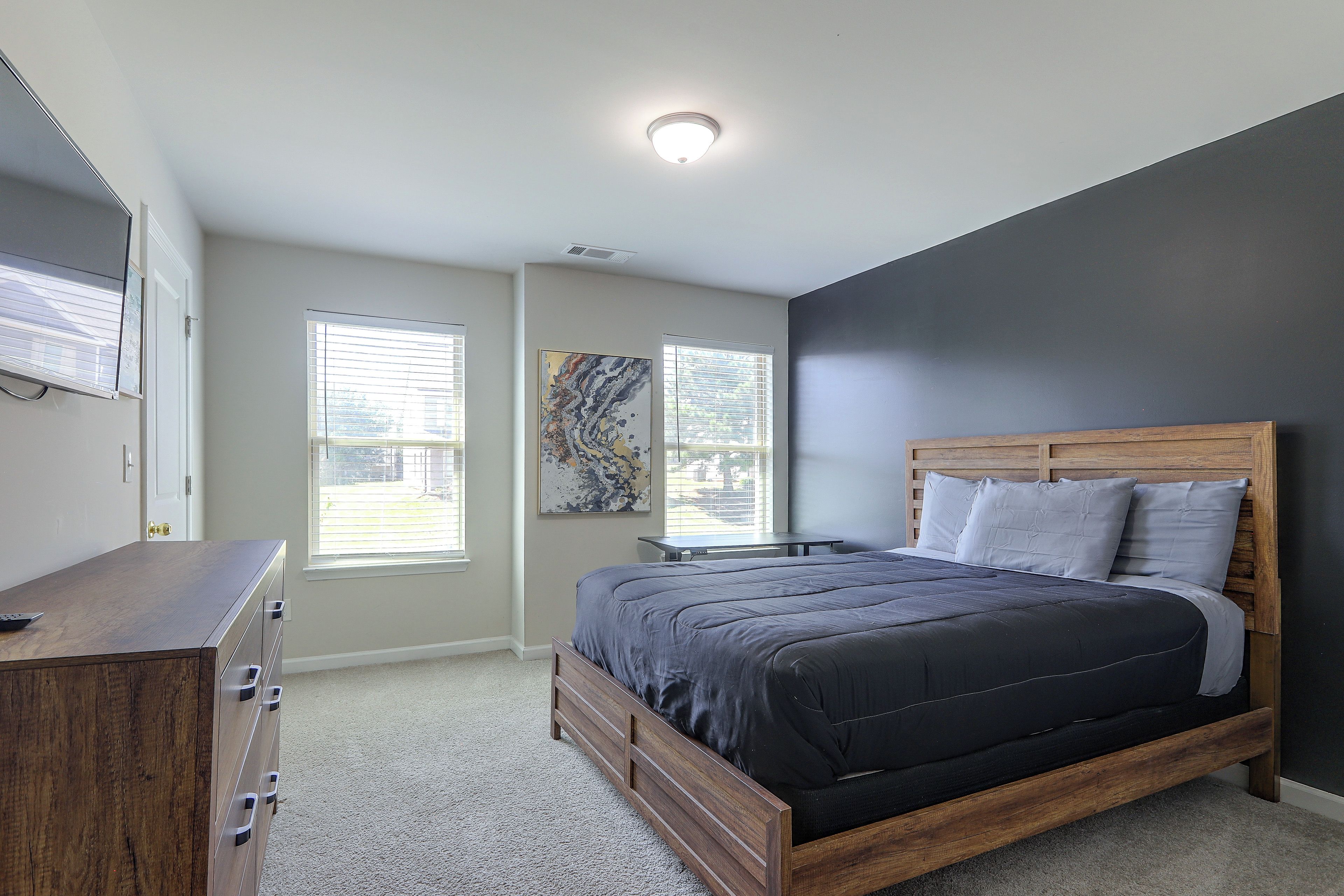 Une chambre à coucher avec un lit, une commode et des œuvres d’art accrochées au mur.
