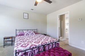 Un dormitori amb un llit, una tauleta de nit, un calefactor fixat a la paret i una porta que condueix a una altra habitació.