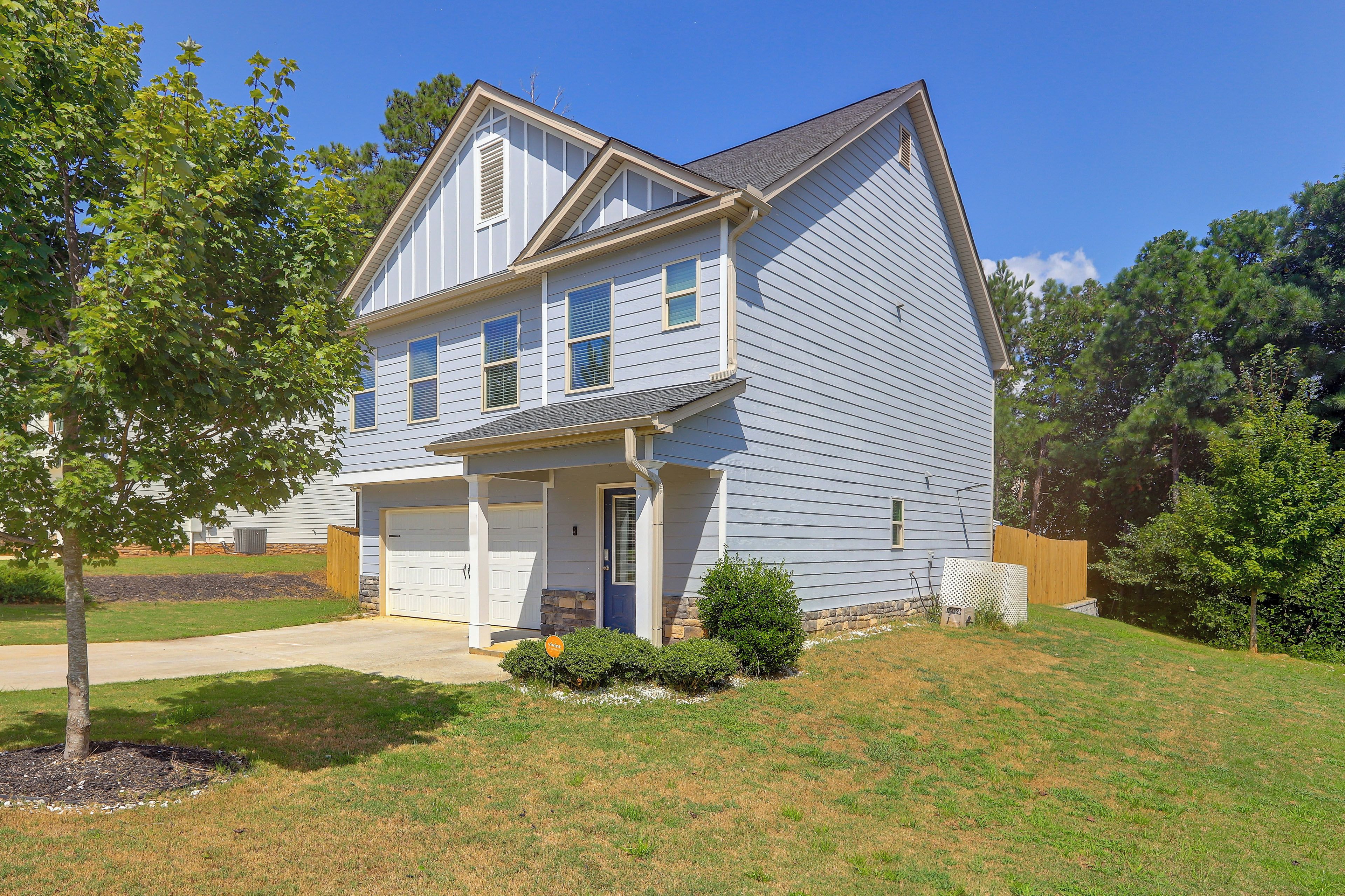 A two-story house with a garage, a front porch, and a well-maintained lawn.