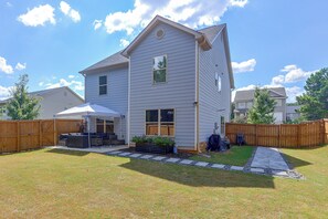 A two-story residential building with a covered patio area, a wooden fence, and a stone pathway leading to the entrance.