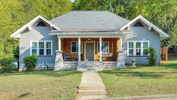 A two-story house with a front porch, a stone foundation, and a well-maintained lawn.