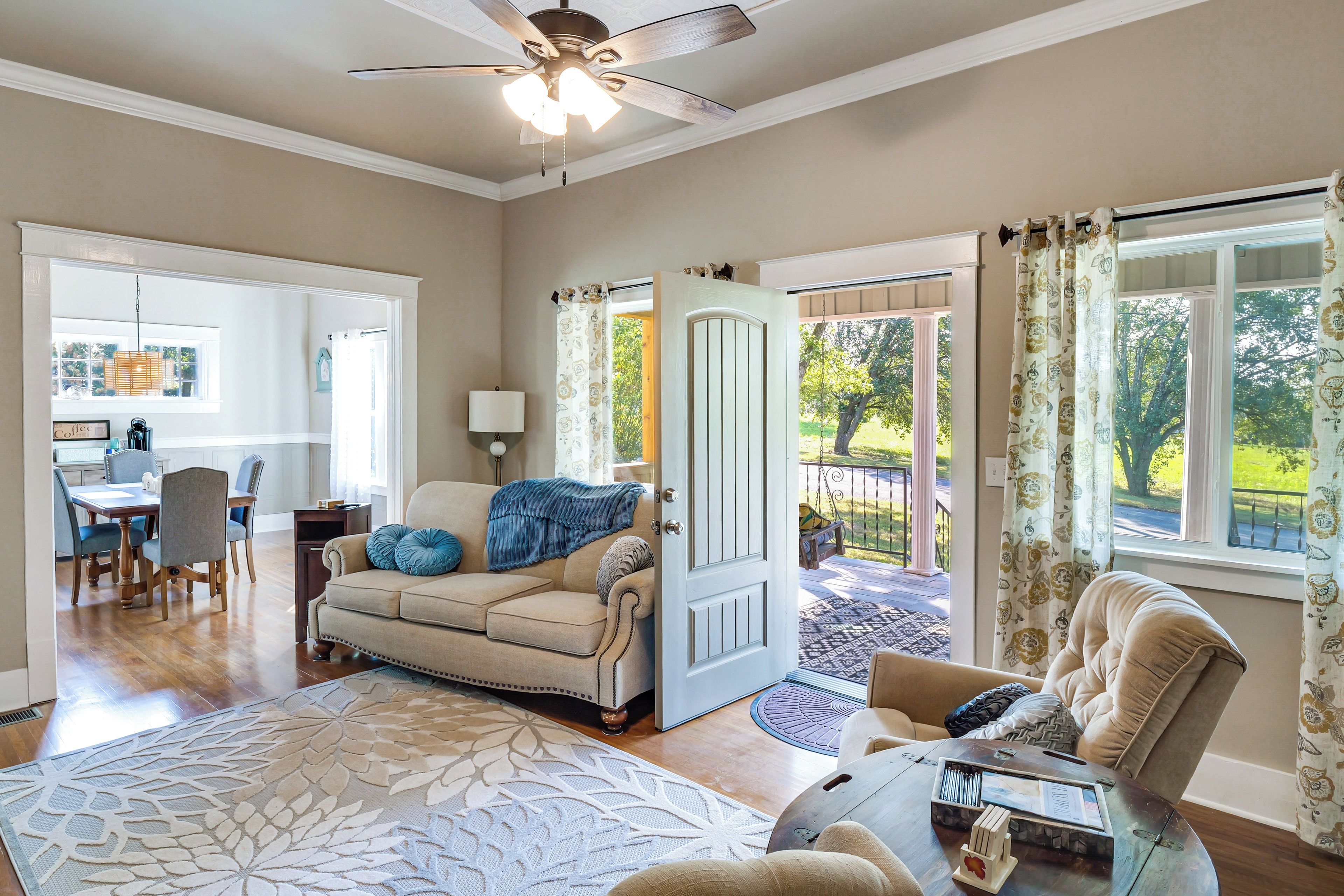 A spacious living room with a beige sofa, a coffee table, and a dining area with a wooden table and chairs.