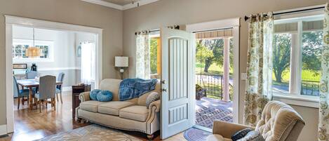 A spacious living room with a beige sofa, a coffee table, and a dining area with a wooden table and chairs.