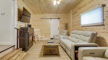 A wooden interior with a sofa, a television, and a fireplace.