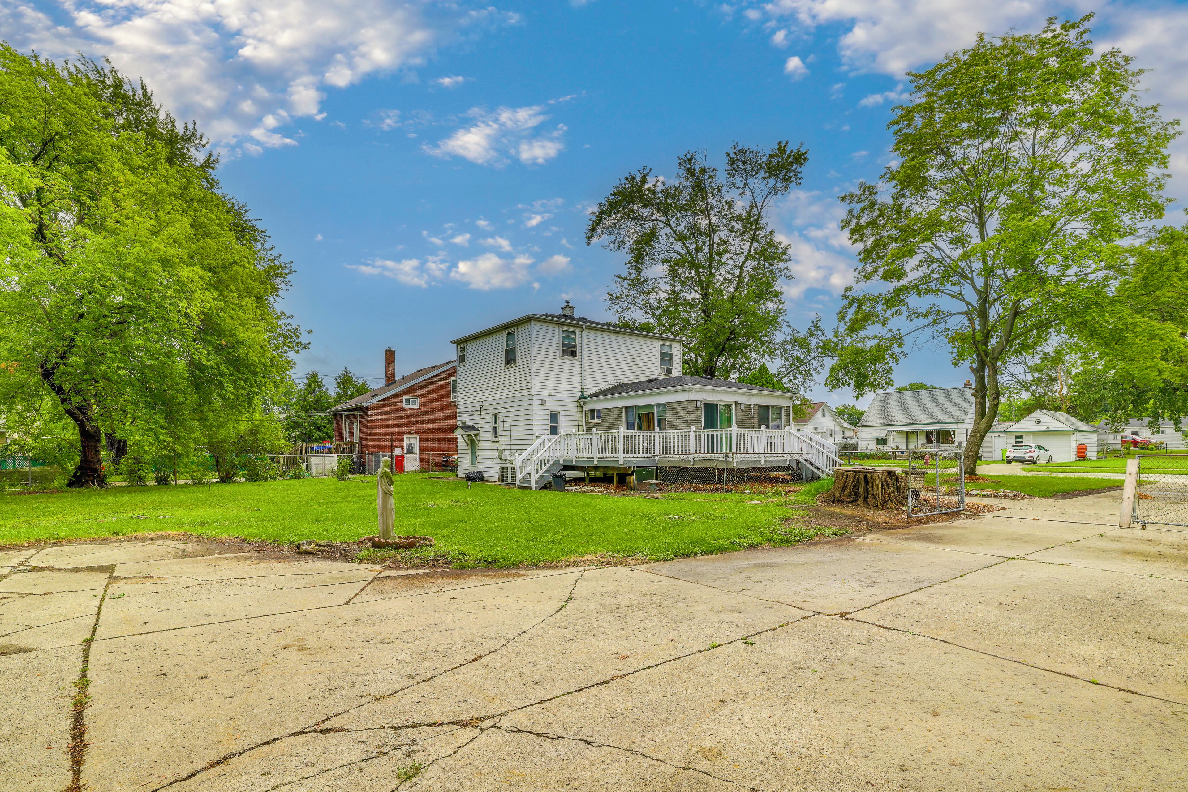 A residential area with a two-story house featuring a porch and a fenced yard.