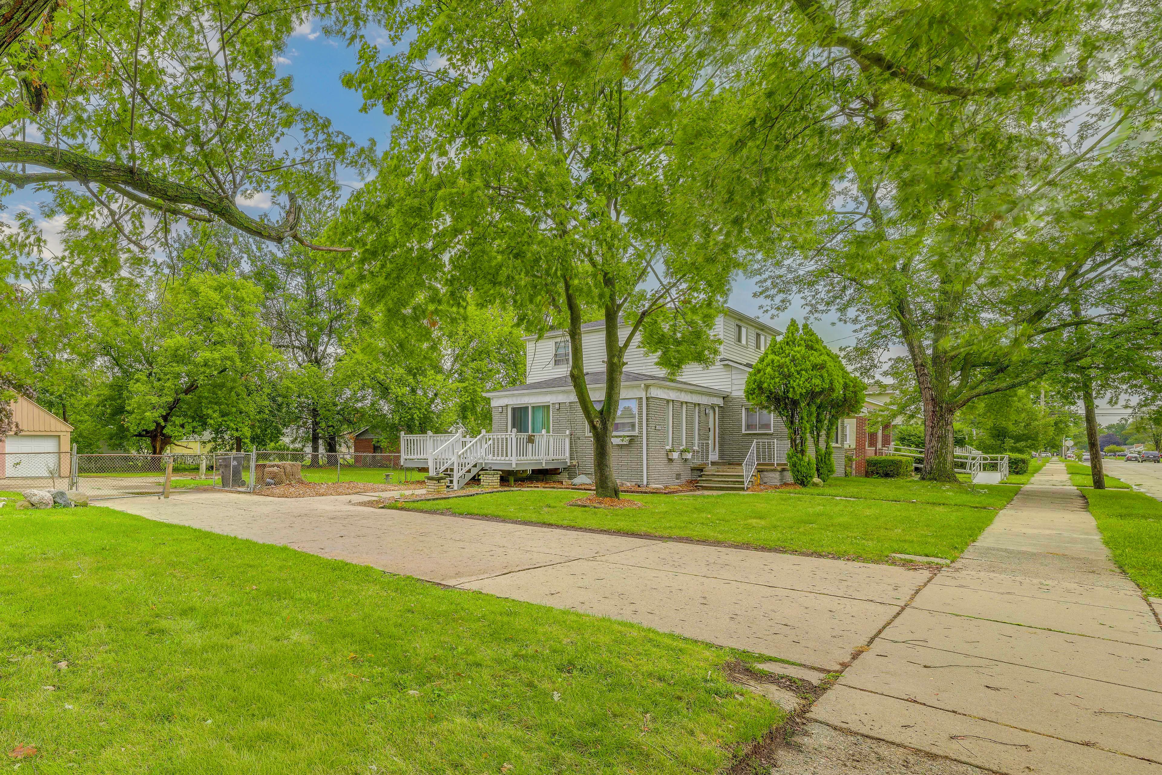 A residential area with a two-story house, a covered porch, and a sidewalk.