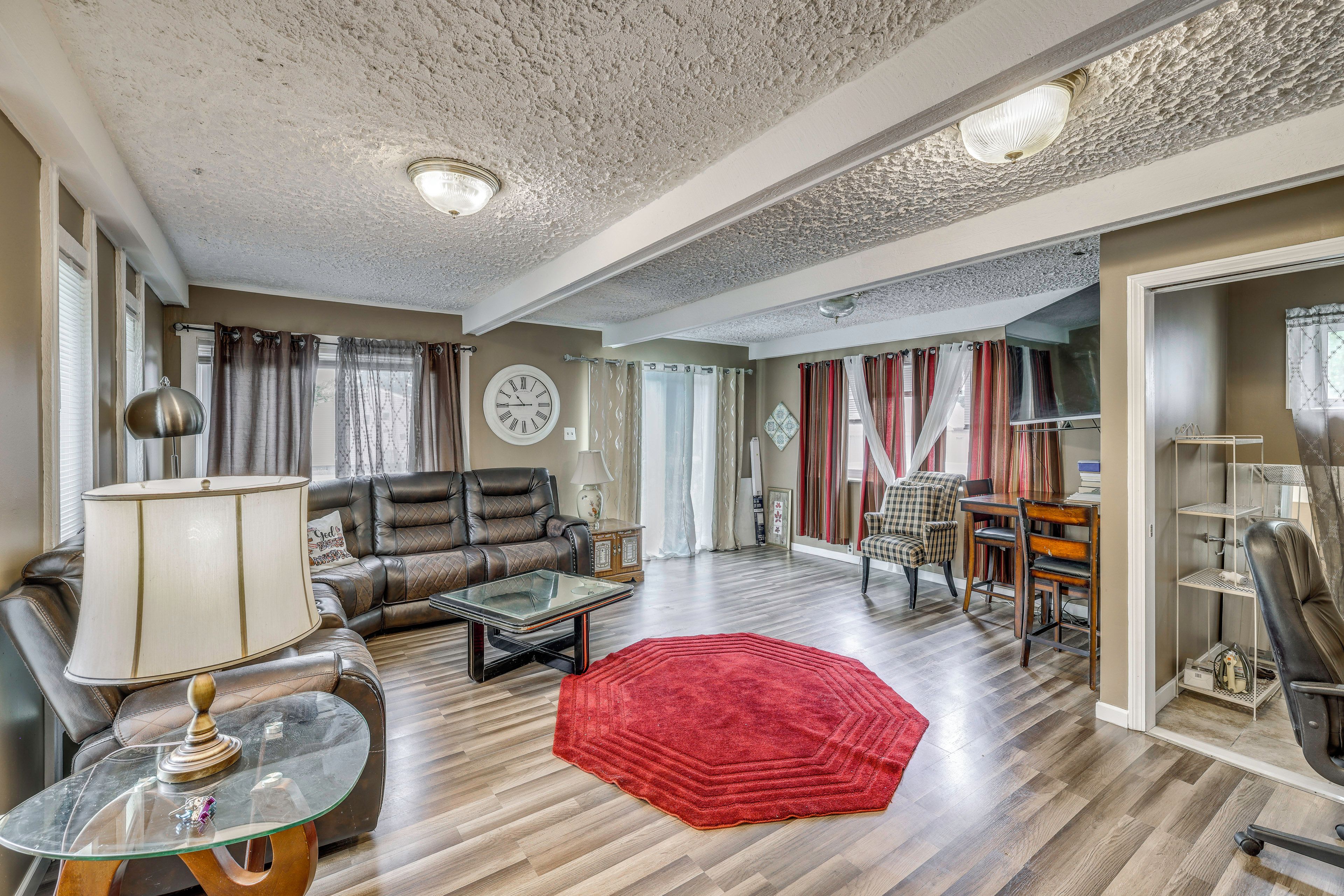 A spacious living room with a leather sofa, a glass coffee table, and a red rug.