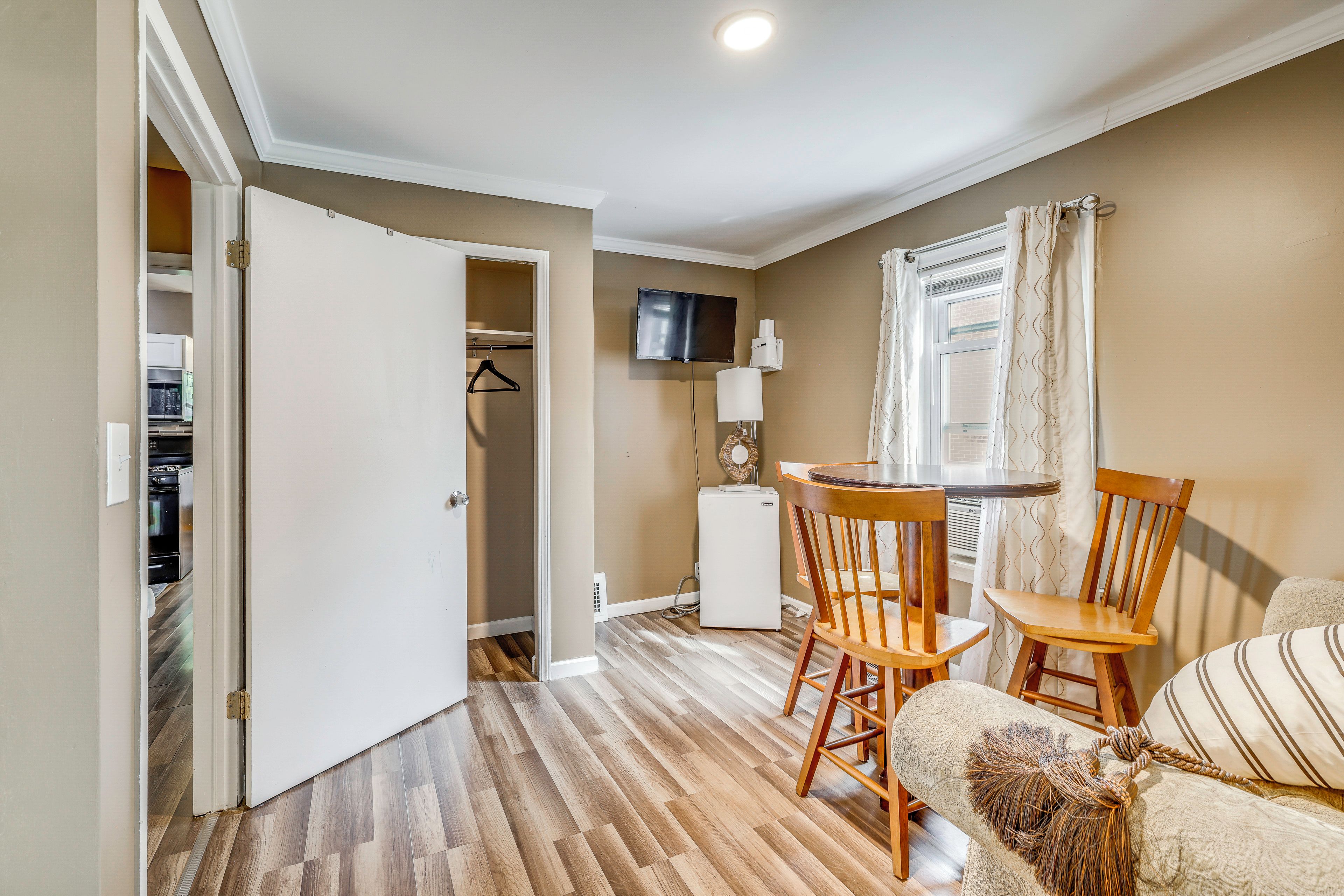 Un espacio habitable compacto con comedor, kitchenette y televisor en la pared.