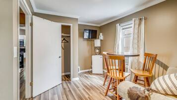 Un espacio habitable compacto con comedor, kitchenette y televisor en la pared.
