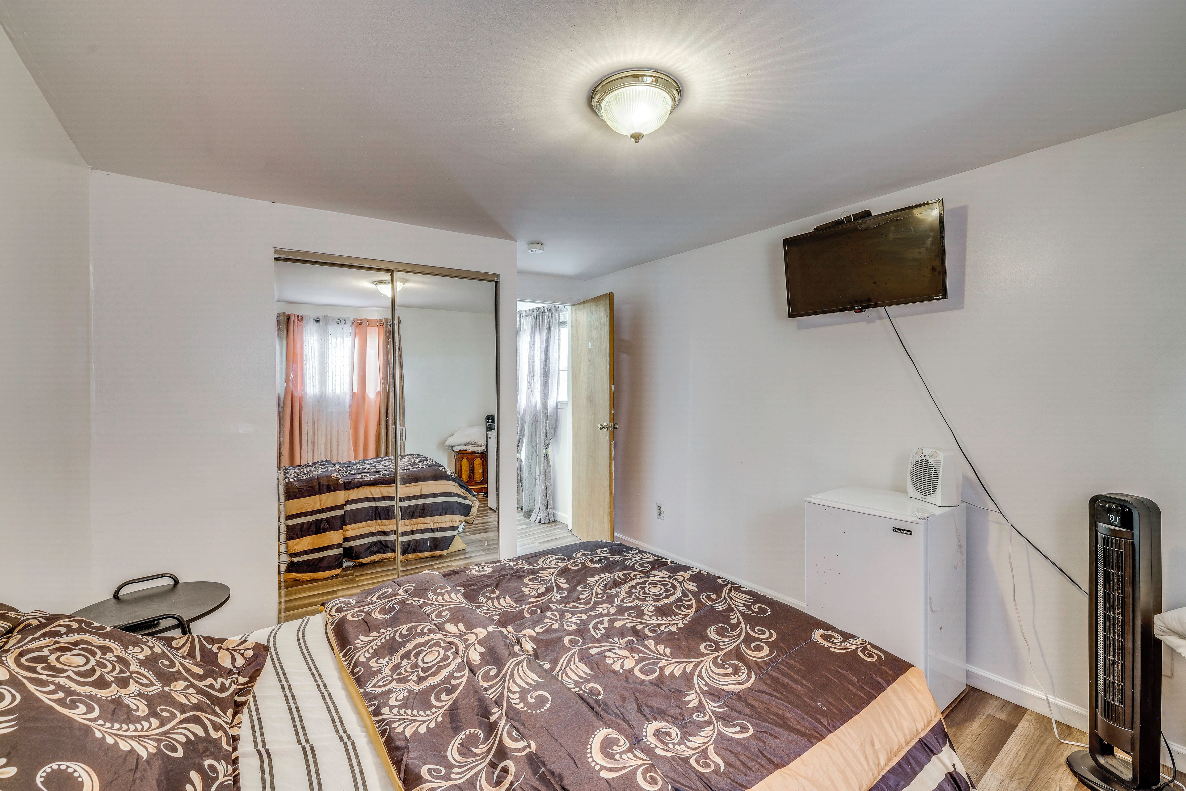 A bedroom with a bed, a television mounted on the wall, and a heater on the floor.