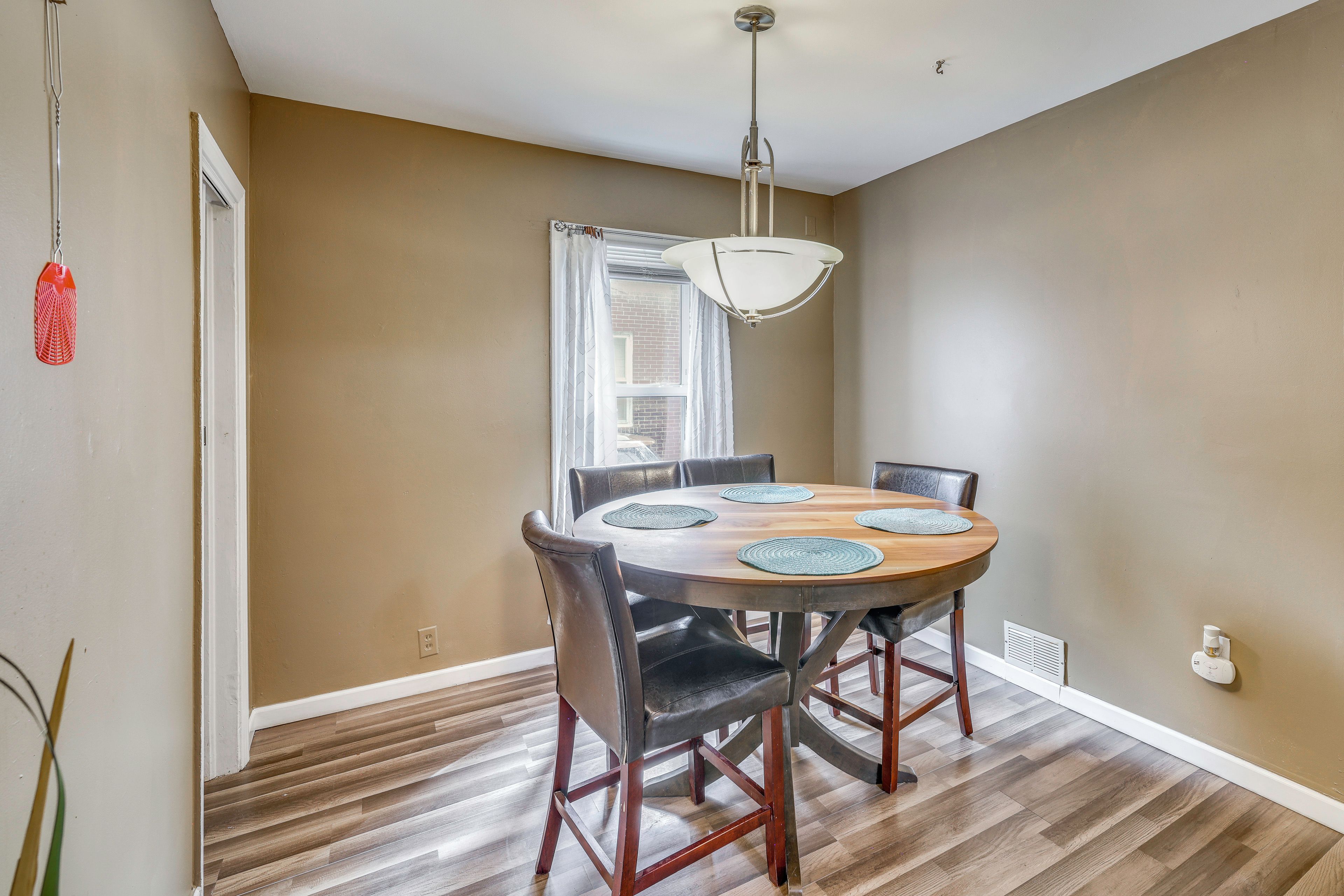 A dining area with a round table, chairs, and a ceiling light fixture.