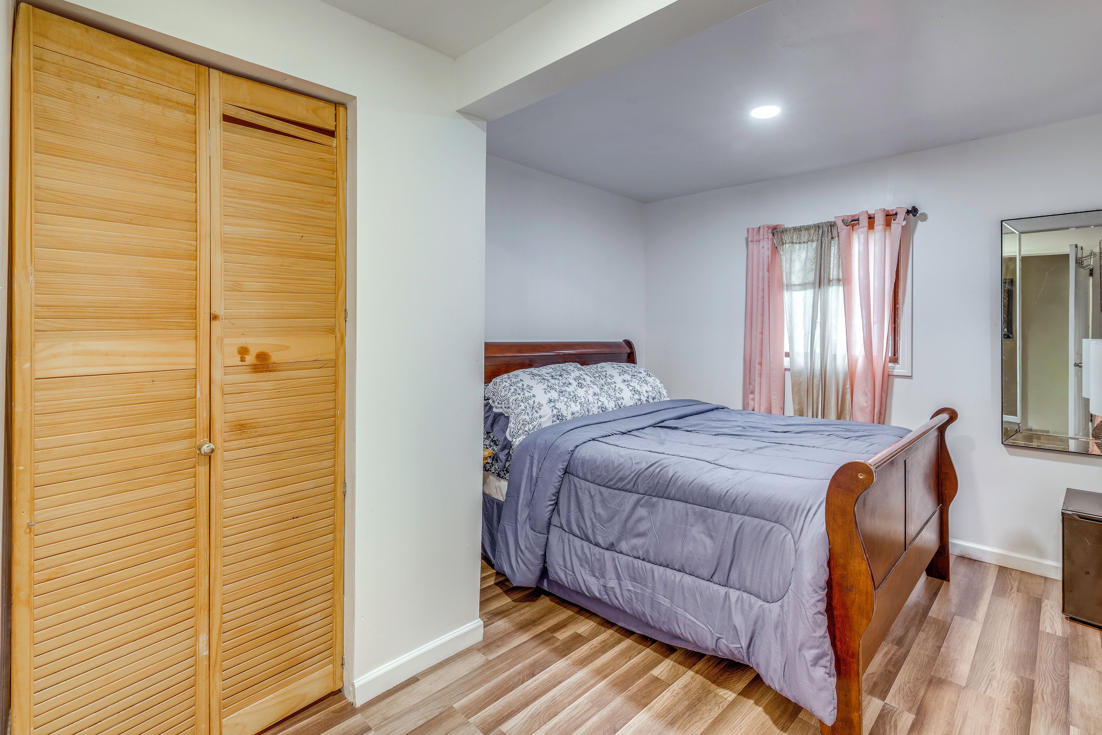 Un dormitorio con un armario de madera, una cama con edredón estampado y un espejo en la pared.