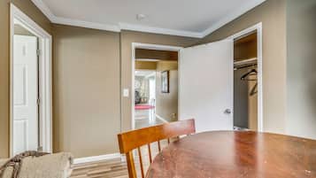 Un comedor con mesa y sillas de madera, un armario para abrigos y una puerta que da a otra habitación.