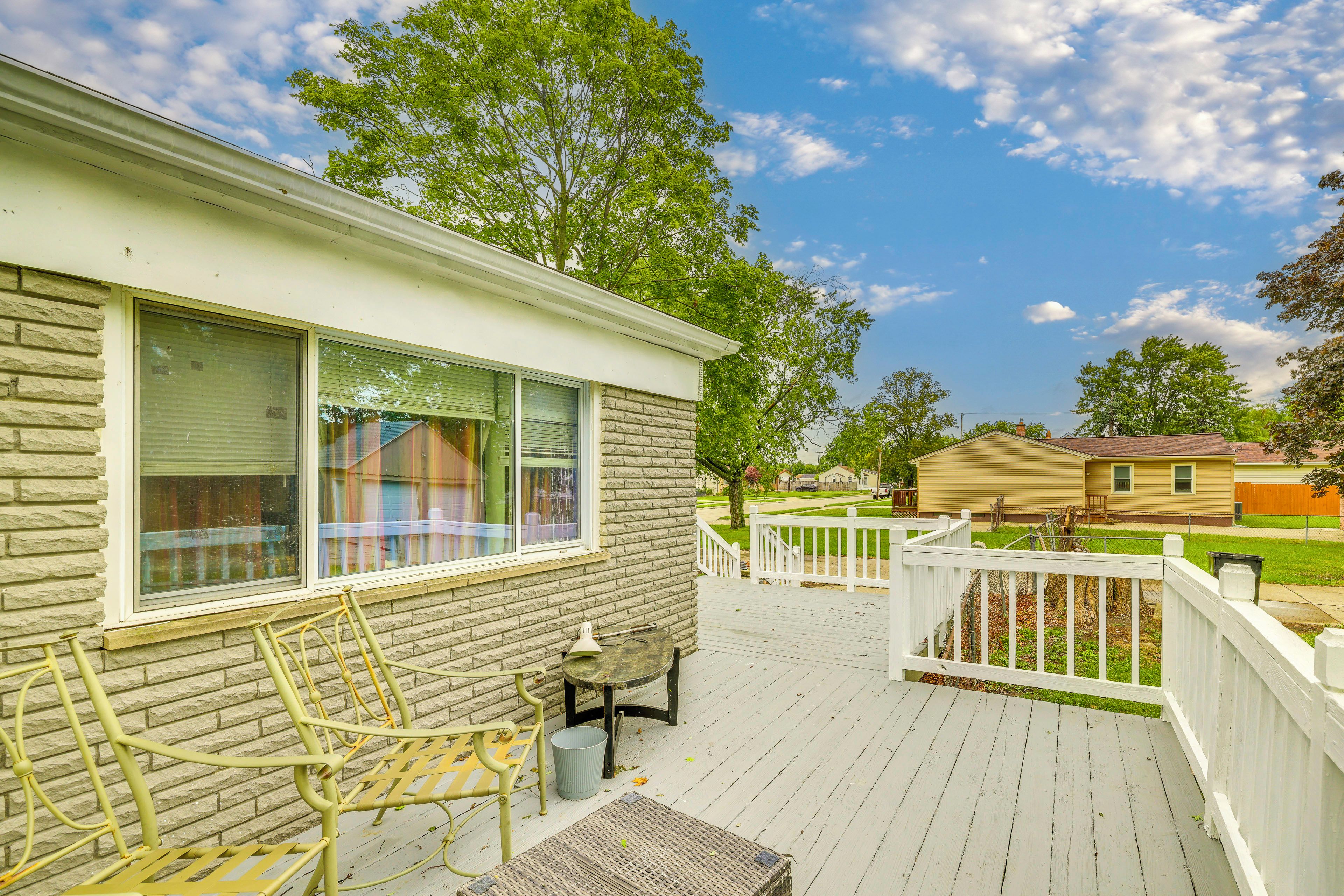A residential deck with a white railing, a wicker chair, and a small table.
