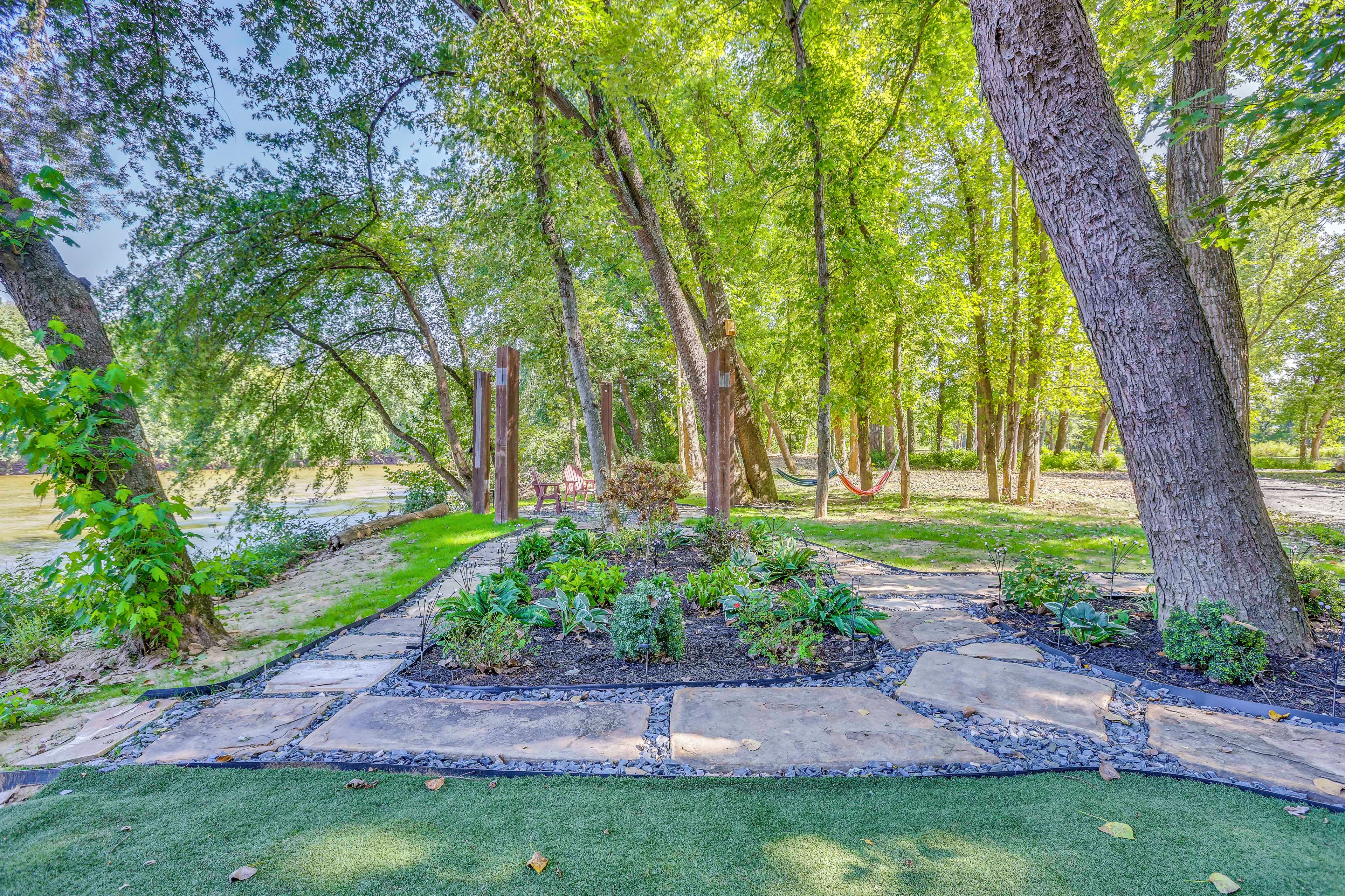 Un jardín con un sendero de piedra, césped verde y árboles.