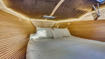 A bed with a wooden headboard and a ceiling with a skylight.