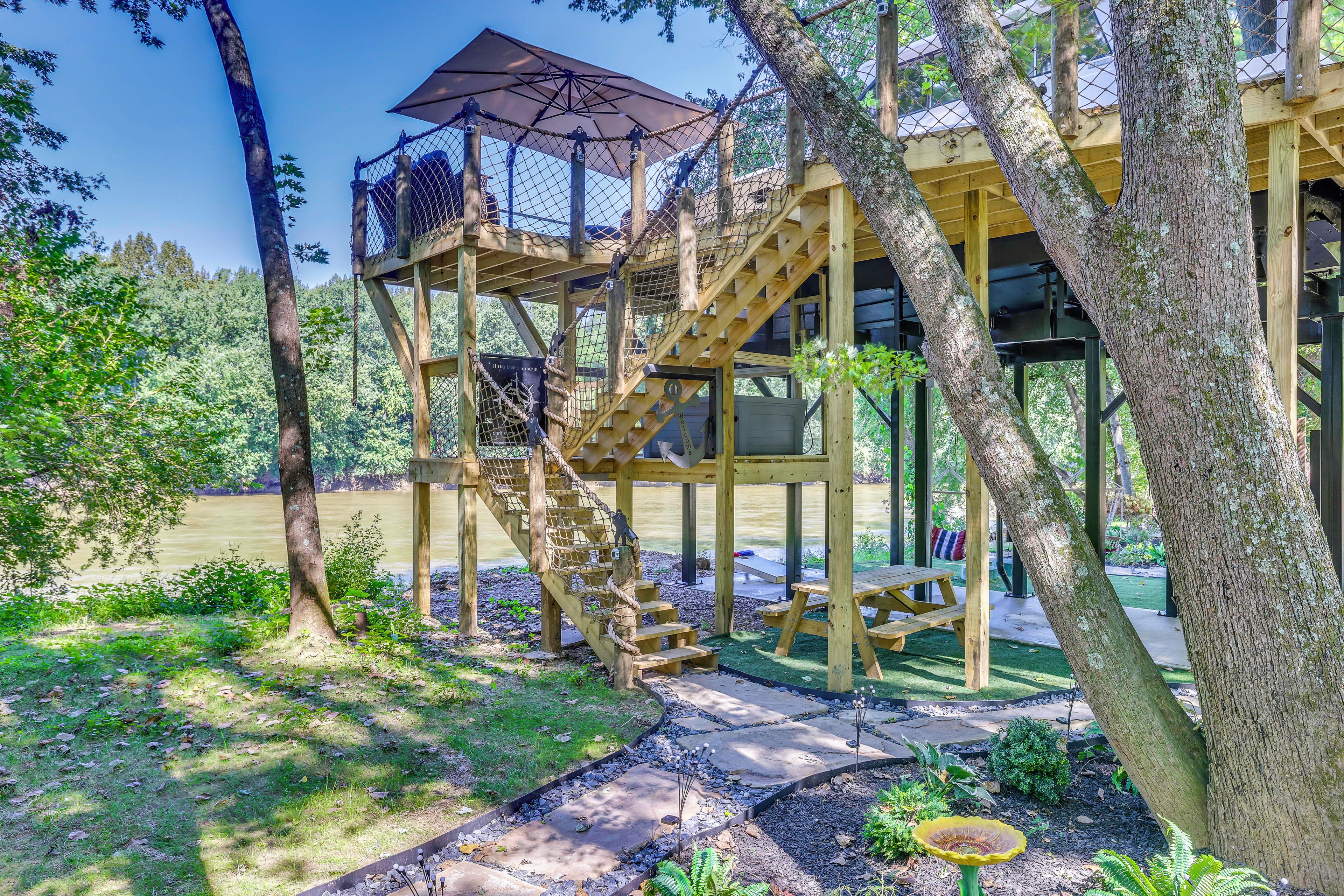 A wooden outdoor structure with a staircase, picnic table, and a covered area with an umbrella.