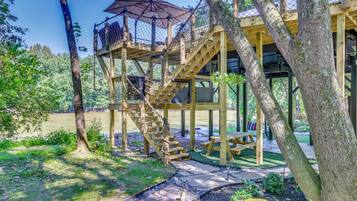 A wooden outdoor structure with a staircase, picnic table, and a covered area with an umbrella.