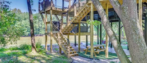 A wooden outdoor structure with a staircase, picnic table, and a covered area with an umbrella.