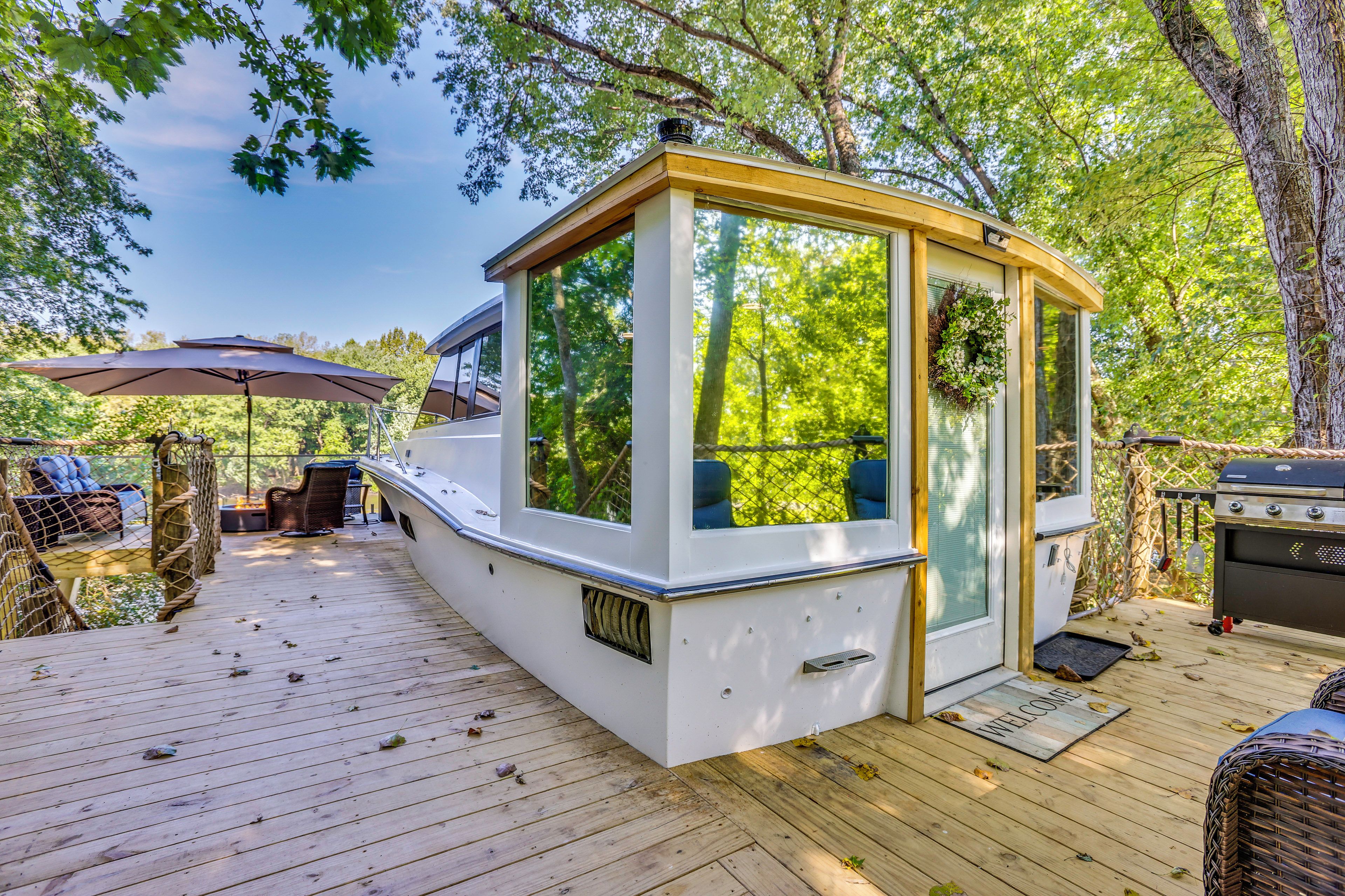 A covered deck area with a white structure, possibly a small room or office, with a door and windows overlooking a wooded area.