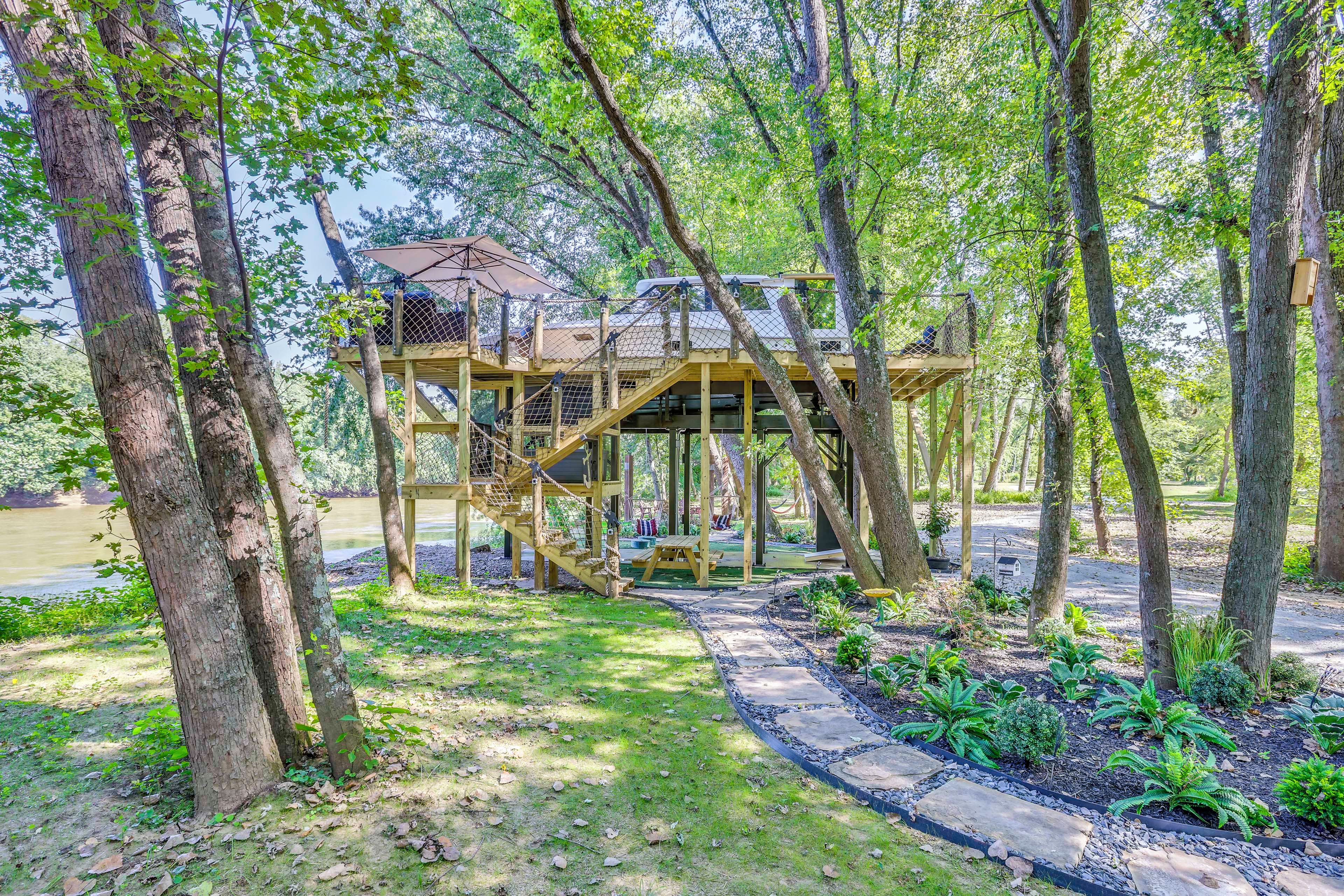 A wooden treehouse structure with a rope bridge and a picnic table.