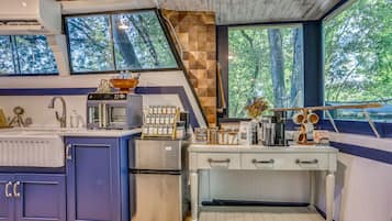 A modern kitchen with a built-in stove, a refrigerator, and a coffee station.