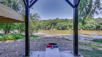 A covered outdoor seating area with a view of a river and forest.