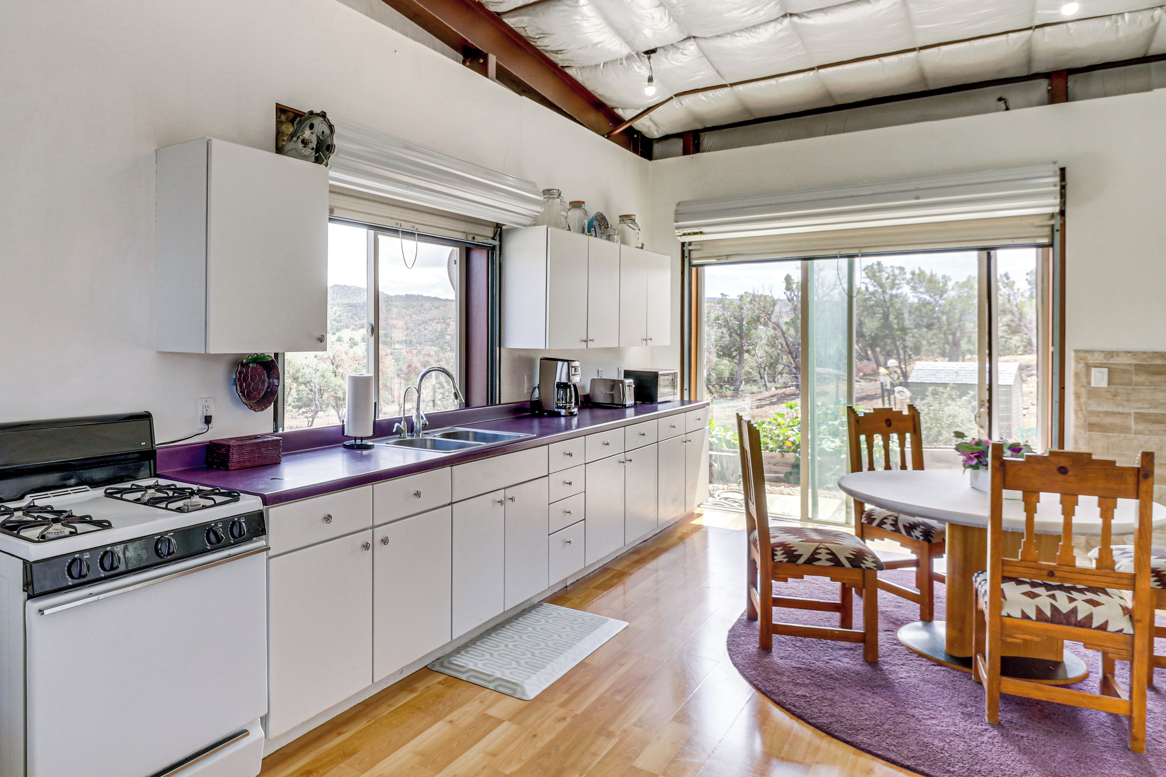 A modern kitchen with a gas stove, white cabinets, and a large window.