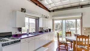 A modern kitchen with a gas stove, white cabinets, and a large window. - Off-grid New Mexico Hideaway Off Hwy 60 (Pie Town)