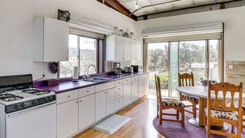 A modern kitchen with a gas stove, white cabinets, and a large window.