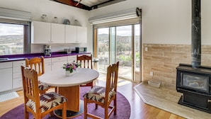 A modern kitchen with a dining area, a large window, and a wood-burning stove. - Off-grid New Mexico Hideaway Off Hwy 60 (Pie Town)