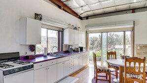 A modern kitchen with a gas stove, white cabinets, and a large window. - Off-grid New Mexico Hideaway Off Hwy 60 (Pie Town)