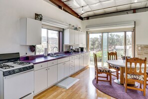 A modern kitchen with a gas stove, white cabinets, and a large window.