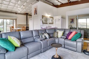 Una sala moderna con un sofá seccional gris, una mesita auxiliar y un ventanal con vistas al exterior.
