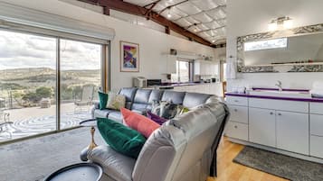 A modern living area with a leather sofa, a dining table, and a kitchen with white cabinets.