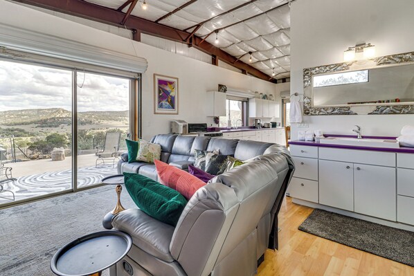 A modern living area with a leather sofa, a dining table, and a kitchen with white cabinets.