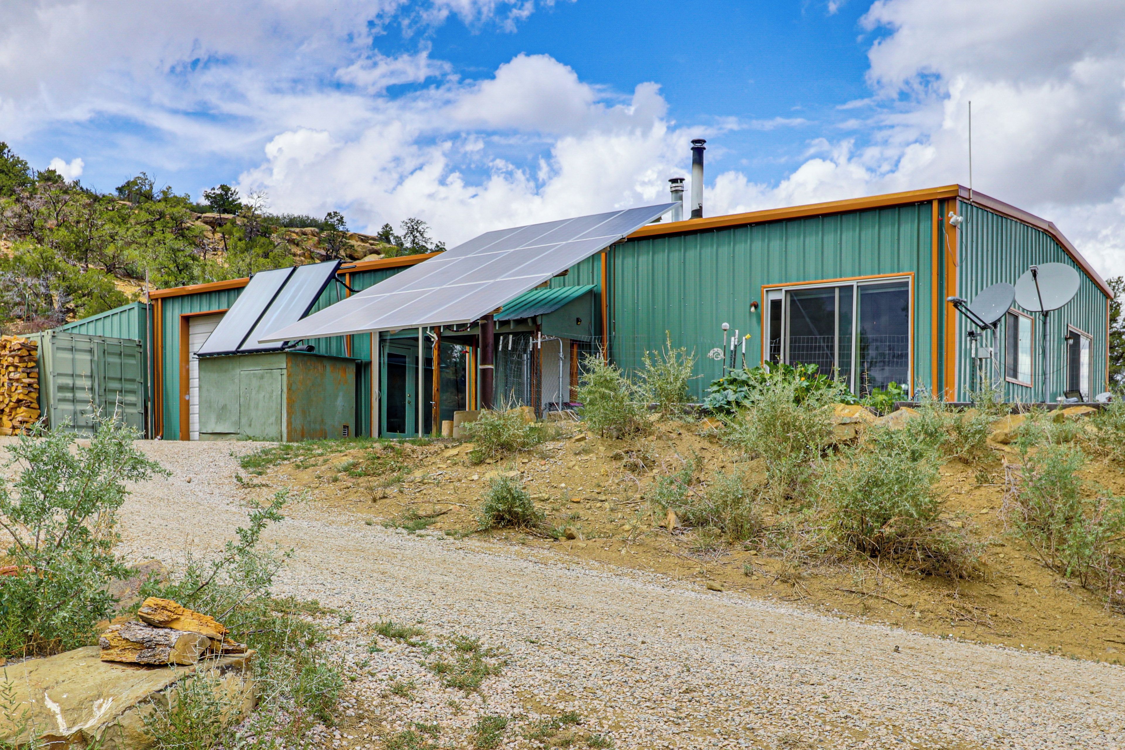 A modern house with solar panels, a large window, and a green exterior.